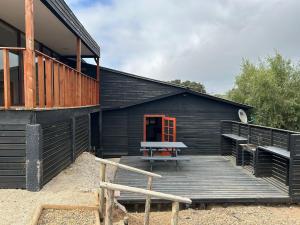 a black building with a bench on a wooden deck at Maitencillo, amplía y cómoda casa, con piscina y hoy tub in Puchuncaví