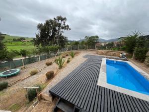 a pool with a wooden deck next to a yard at Maitencillo, amplía y cómoda casa, con piscina y hoy tub in Puchuncaví