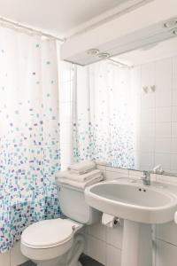 a white bathroom with a toilet and a sink at Apart Hotel Sendero del Sol in La Serena