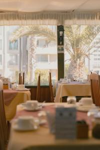 a restaurant with white tables and chairs and a palm tree at Apart Hotel Sendero del Sol in La Serena