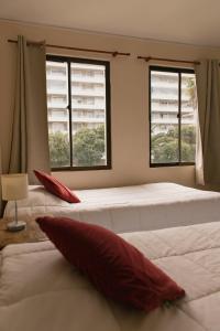a bedroom with two beds and two windows at Apart Hotel Sendero del Sol in La Serena
