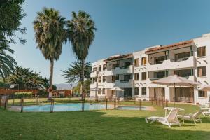 a hotel with a swimming pool and palm trees at Apart Hotel Sendero del Sol in La Serena +26 photos