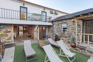 a patio with white chairs and a building at T5 com Piscina Casa da Chica in Espiunca
