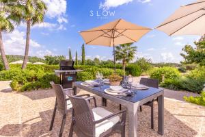 a table and chairs with an umbrella and a grill at Villa Cas Frares by Slow Villas in Consell