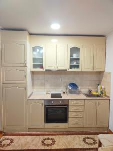 a kitchen with white cabinets and an oven at Look Apartman in Vrnjačka Banja