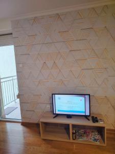 a flat screen tv sitting on a table in front of a wall at Look Apartman in Vrnjačka Banja