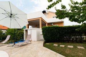 een patio met 2 stoelen en een parasol voor een huis bij Villa Bistre in Radovin