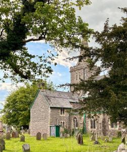 an old stone church with a tower in a cemetery at Charming 2 bedroom cottage in Brecon - families and pets welcome! in Brecon