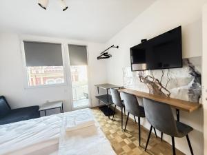 ein Zimmer mit einem Bett, einem Schreibtisch mit Stühlen und einem Fernseher in der Unterkunft Ma Bel Apartments Sarajevo in Sarajevo