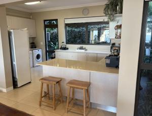 a kitchen with a counter and two stools at Beach Blessing - 180° Sea Views in Blythedale