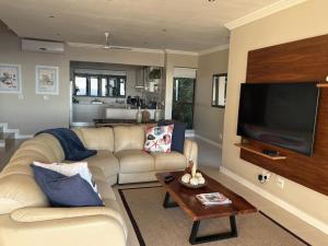 a living room with a couch and a flat screen tv at Beach Blessing - 180° Sea Views in Blythedale
