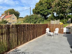 a patio with two chairs and a fence at The Nestle - A Romantic Rural Retreat in Ilminster