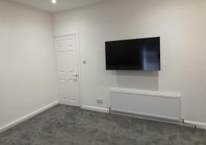 Habitación blanca con TV de pantalla plana en la pared en 81b Queens Road, en Watford