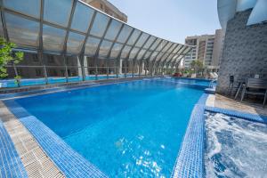 a large pool with blue water in front of a building at Wahaj Boulevard Hotel Apartmentوهج بوليفارد للشقق الفندقية in Kuwait +24 photos