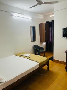 une chambre avec un lit et une chaise dedans dans l'établissement Vinayaka Tourist Home, à Kozhikode