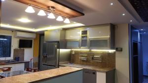 a large kitchen with stainless steel appliances and lights at Appartement des Palmiers in Biskra +3 photos