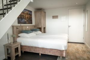 a bedroom with a large bed and a staircase at Het Hart van Weesp in Weesp