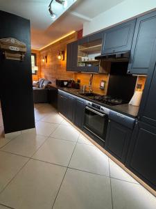 a kitchen with black cabinets and a white tile floor at Appartement cosy entre lacs et montagnes in Guillestre +2 photos