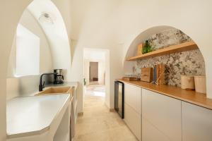 Una cocina con gabinetes blancos y un fregadero. en Trulli D'Amore - Itria Valley Exclusive Trulli Villa, en Santa Lucia