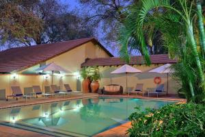 a swimming pool with chairs and umbrellas next to a building at Raydia Ventures Travel and Tours in Livingstone
