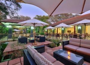an outdoor patio with couches and tables and umbrellas at Raydia Ventures Travel and Tours in Livingstone