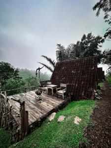 a wooden deck with a table and a bench on it at KAMPUNG KOPI CAMP in Pujungan