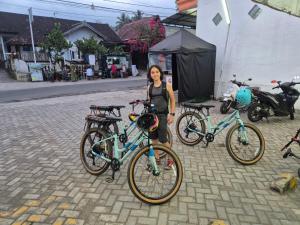 a woman standing next to two bikes on a street at Stay Together in Tetebatu