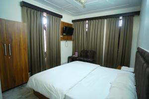 Un dormitorio con una cama blanca y algunas cortinas en Baba Devtal Homestay, en Bhimtal 7 fotos más