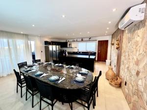 a dining room with a table and chairs and a kitchen at Uhane Grand Villa 7 Quartos, Piscina e Vista Mar in São Miguel do Gostoso