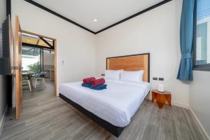 a bedroom with a bed with two towels on it at Stylish Eco Villa Sunset Garden 1E with Private Pool near Nai Harn Beach in Ban Saiyuan (1)