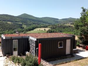 a rendering of a black tiny house with mountains in the background at Maison-containers en Nord-Ardèche in Saint-Félicien