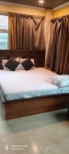 a bed with white sheets and pillows in front of a window at Hotel airport stay heavens in kolkata