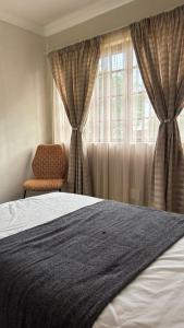 une chambre avec un lit, une chaise et une fenêtre dans l'établissement The N1 Farm Place, à Pretoria