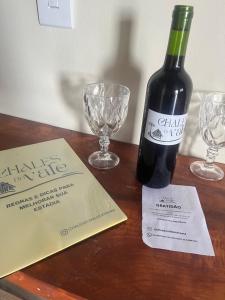 a bottle of wine and two glasses on a table at Chalés do vale Extrema Cinza in Extrema