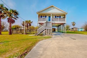 a house with palm trees and a driveway at Crystal Beach 3BR Comfortable Home w/ Patio, Short Drive to Beach in Crystal Beach