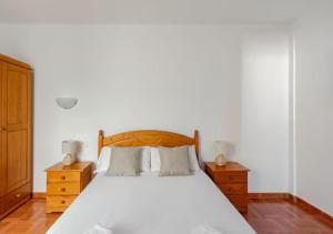 a bedroom with a white bed and two night stands at Los Alisios Amplio y luminos a pasos del mar in Pozo Izquierdo