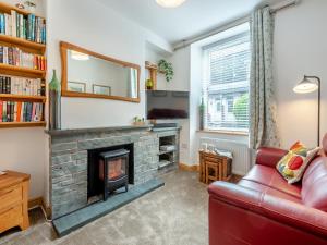 a living room with a fireplace and a red couch at Stanley Cottage in Windermere