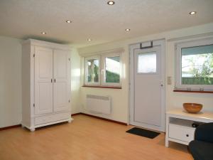 - un salon avec une armoire blanche et des fenêtres dans l'établissement kleiner Holzbungalow Grundmann mit Naturgarten, à Wilhelmsfelde