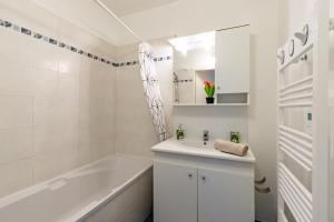 ein weißes Badezimmer mit Badewanne und Waschbecken in der Unterkunft Charming T2 in Frouzins in Frouzins + 21 Fotos