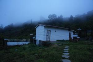 a small white building in a field with a fence at December Holiday inn 1 Bedroom House with 2 tent houses in Kodaikānāl