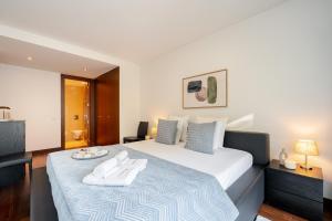 MassarelosにあるPremium Flat w/ Pool, Gym & Garage by HostWiseのベッドルーム1室(大型ベッド1台、白いタオル2枚付)