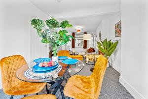 a dining room with a glass table and yellow chairs at Clover House Stunning Cosy Cottage 3BR By AltoLuxo Short Lets & Serviced Accommodation With Free WiFi & Parking in Ebbw Vale +26 photos