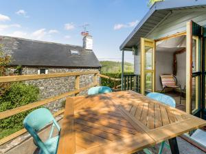 une table et des chaises en bois sur la terrasse d'un chalet dans l'établissement 3 Legged Duck Cottage, à Yspytty-Ystwyth