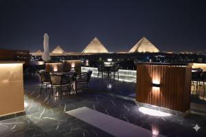 Un patio en la azotea con mesas y sillas por la noche. en Pyramids Sunshine View, en El Cairo