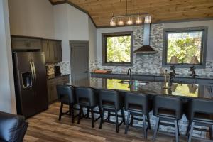 una cocina con una barra con sillas negras. en Beartopia - Private Indoor Pool, Mountain Views, Game Room + Luxury Accommodations, en Oldham
