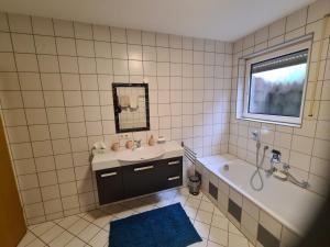 a bathroom with a sink and a tub and a mirror at Ferienwohnung Oskar in Gschwend