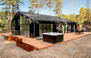 a black house with a hot tub on a wooden deck at Nice Home In Nexø With Sauna in Bedegård