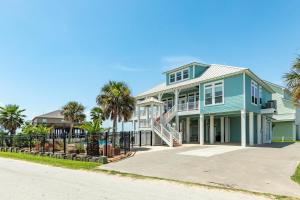 a blue house with palm trees in front of it at Exclusive Pool Gulf Views Modern Cargo Lift in Bolivar Peninsula