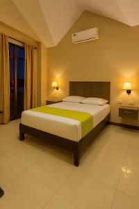 a bedroom with a large bed with a green and yellow blanket at HOTEL MANTA BEACH MADRIGAL in Manta