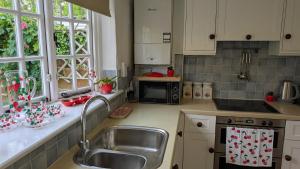 a kitchen with a sink and a microwave at 8 Pudding Bag Lane in Exton
